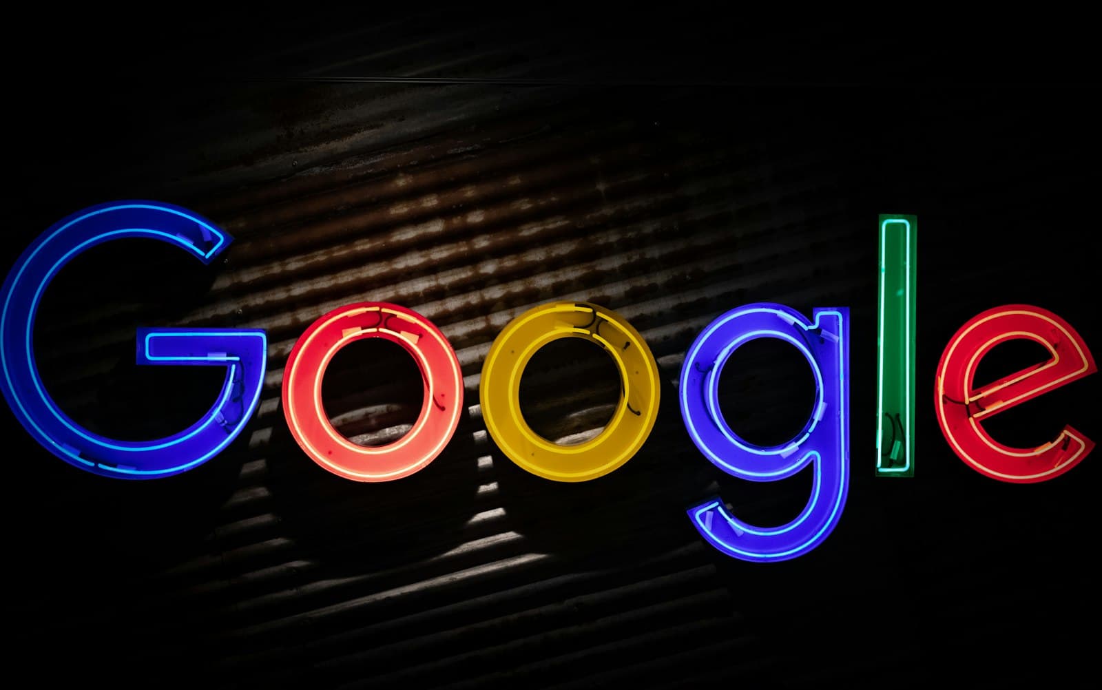 Enseigne au néon reprenant les couleurs du logo Google sur un mur sombre