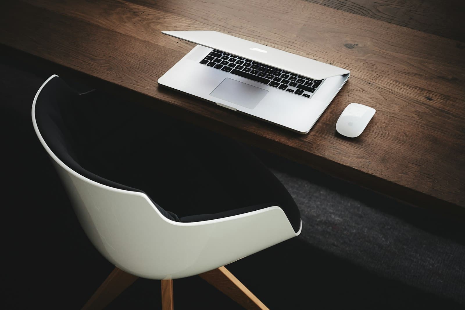 Poste de travail d'une petite structure : ordinateur portable et souris posés sur un bureau en bois