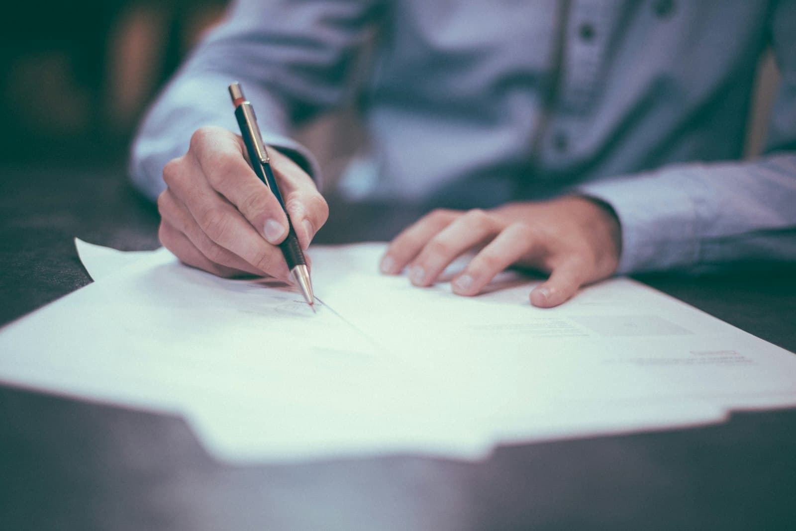 Mains remplissant au stylo un document administratif posé sur un bureau