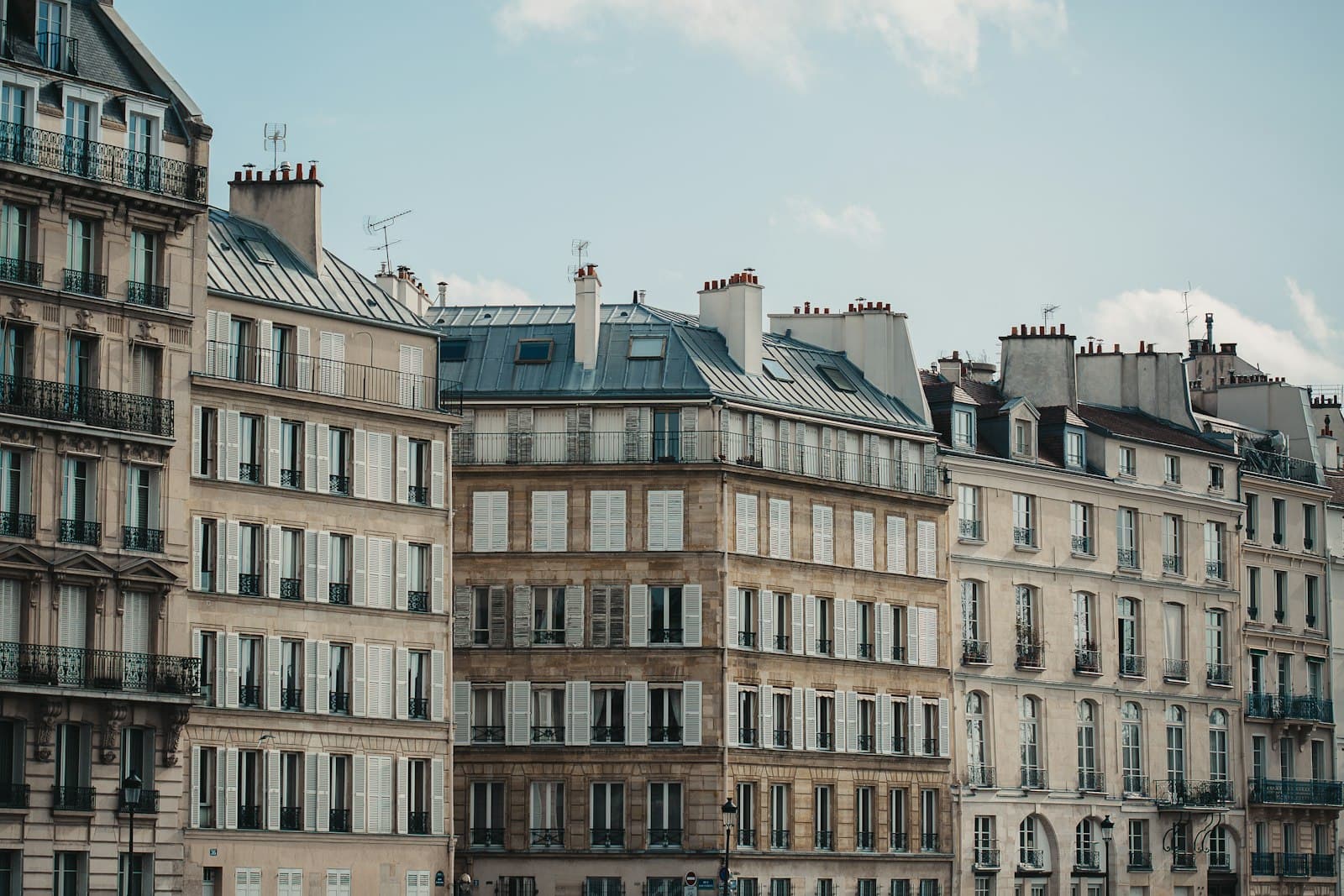 Rangée d'immeubles d'habitation parisiens aux façades claires, avec balcons et toits en zinc