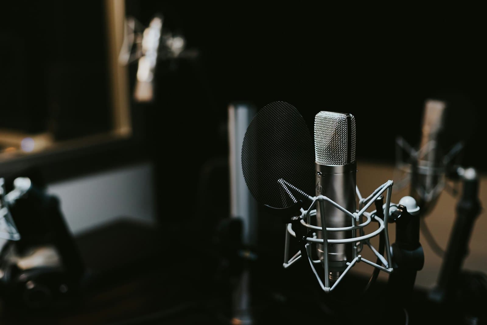Un microphone de studio à condensateur monté sur suspension avec son filtre anti-pop, dans un studio d'enregistrement sombre