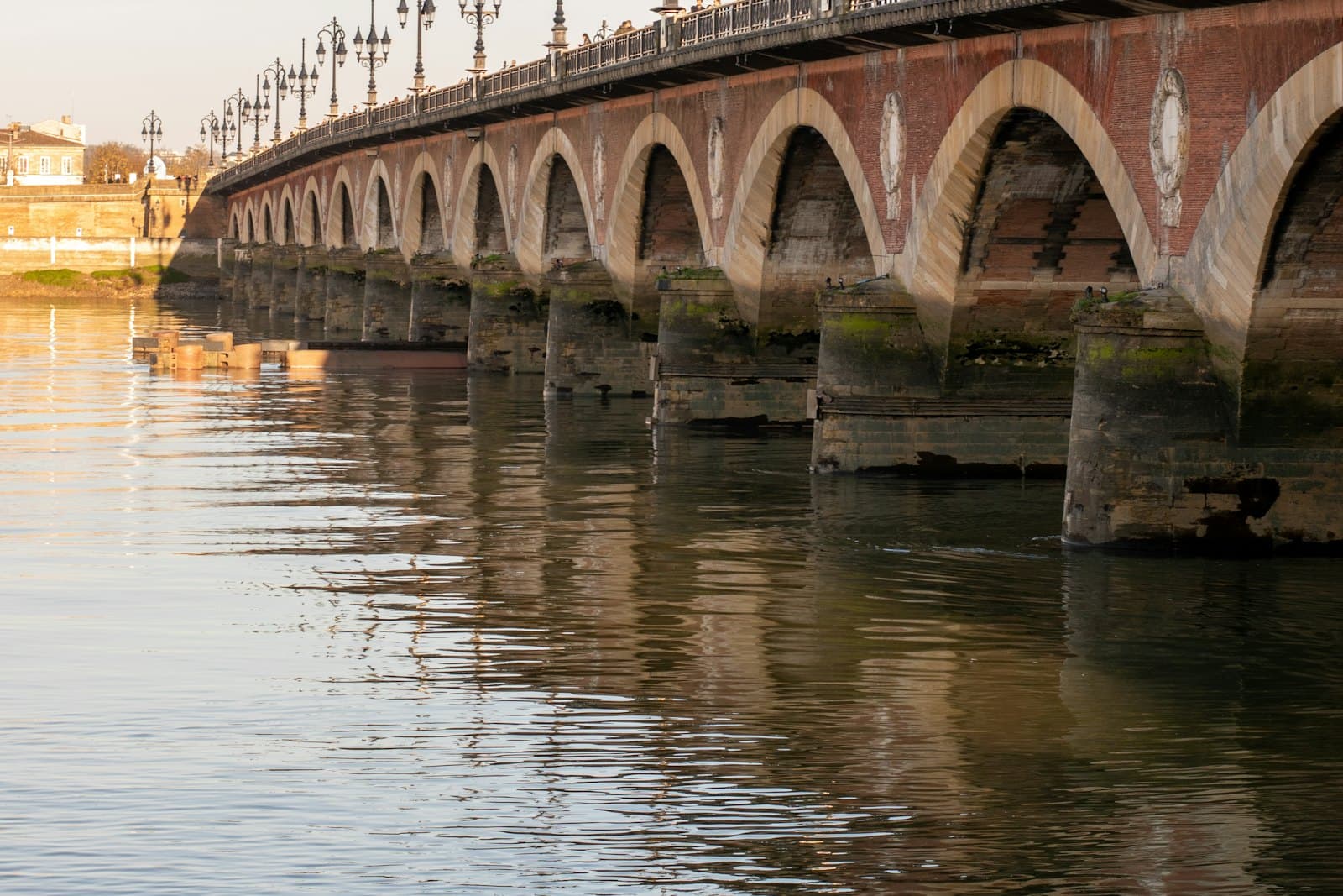 Les arches de brique et de pierre du pont de Pierre se reflétant dans la Garonne, à Bordeaux