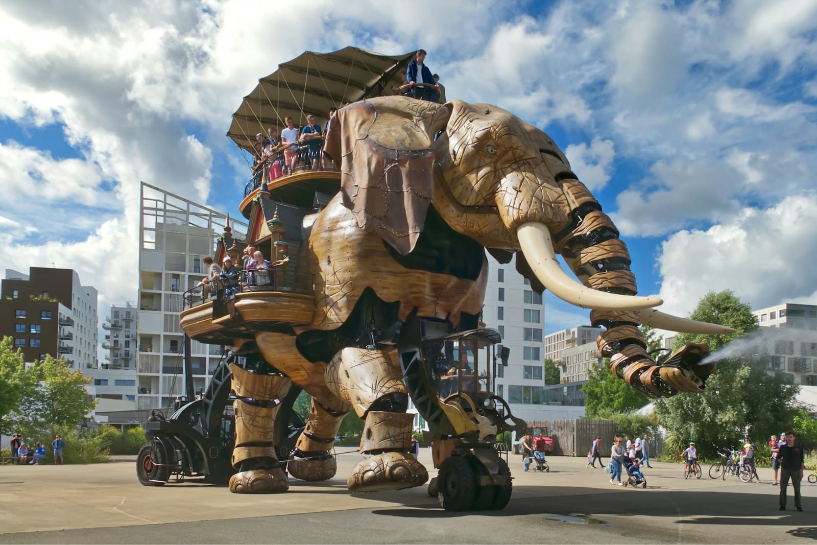 Le Grand Éléphant des Machines de l'île, structure de bois et d'acier portant des visiteurs sur son dos, projetant de l'eau par sa trompe